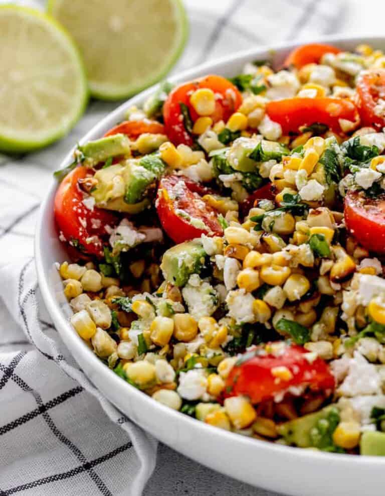 Grilled Corn Salad in White Bowl with limes and Kitchen Towel