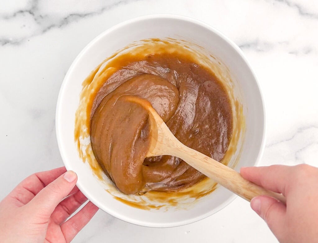 Combining Wet Ingredients for Apple Blondies in White Bowl with Wooden Spoon
