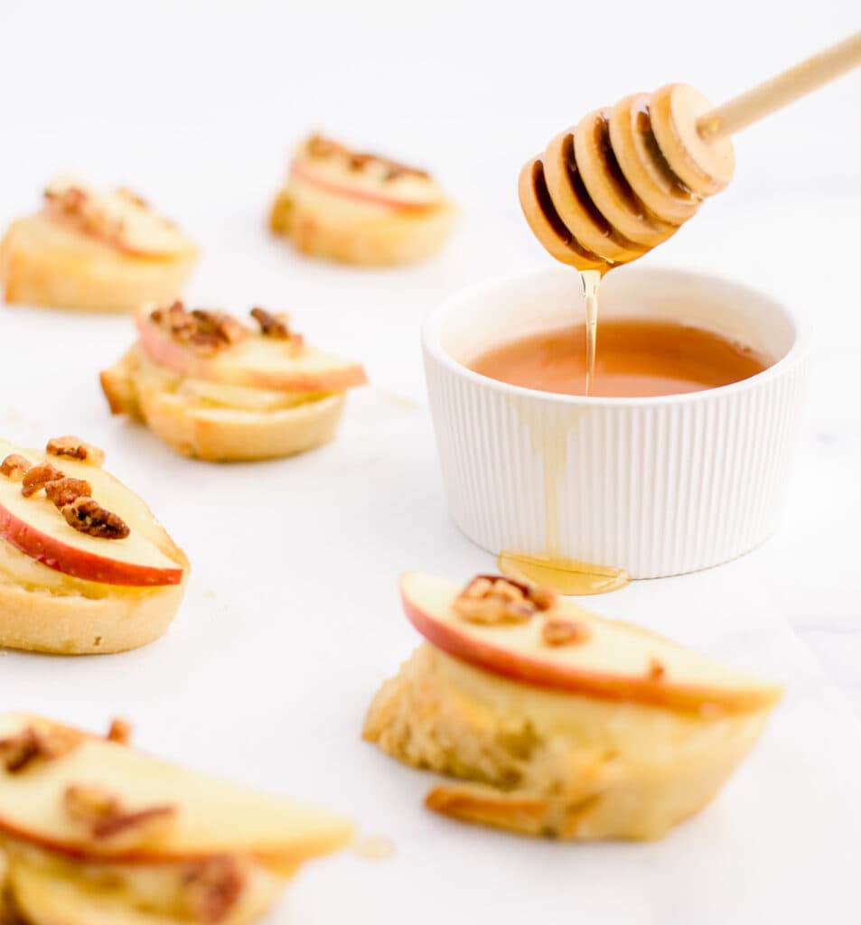 Honey Stick with Cup of Honey Next to Crostini Appetizers