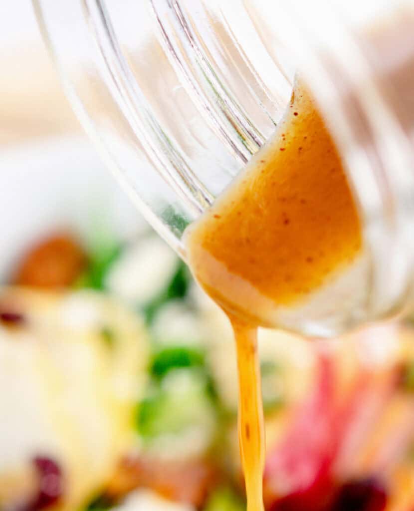 Pouring Apple Cider Vinaigrette from Jar on to Fall Salad