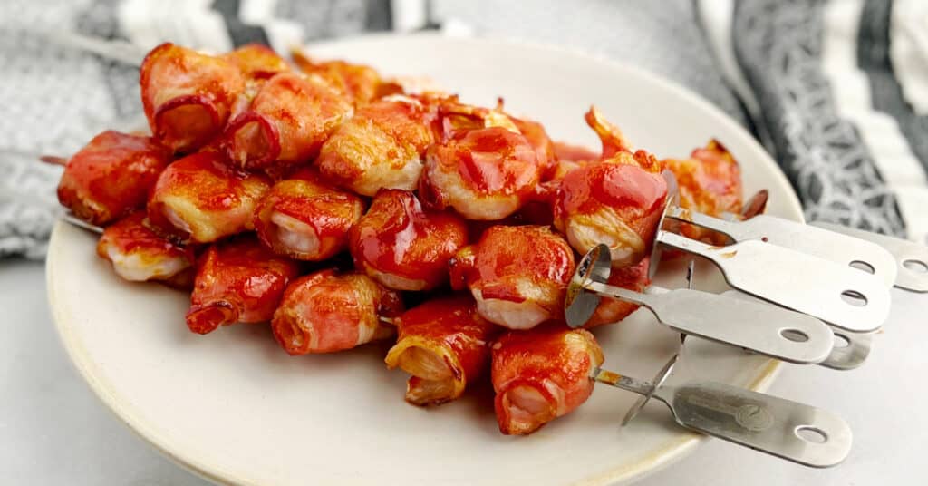 Bacon Wrapped Shrimp Skewers on Plate with Kitchen Towel in the Background