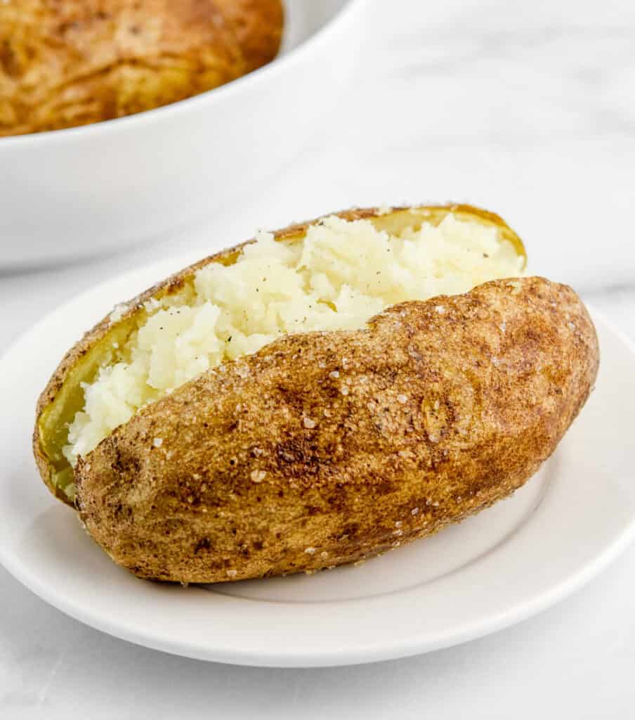 Finished Baked Potato Cut Open and Mashed on White Plate