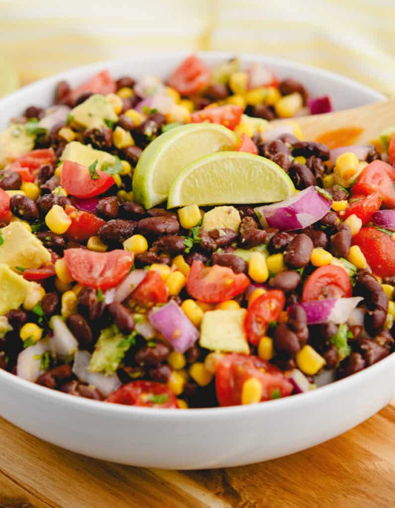 Black Bean Salad in a Bowl With Lime Wedges and Wooden Spoon