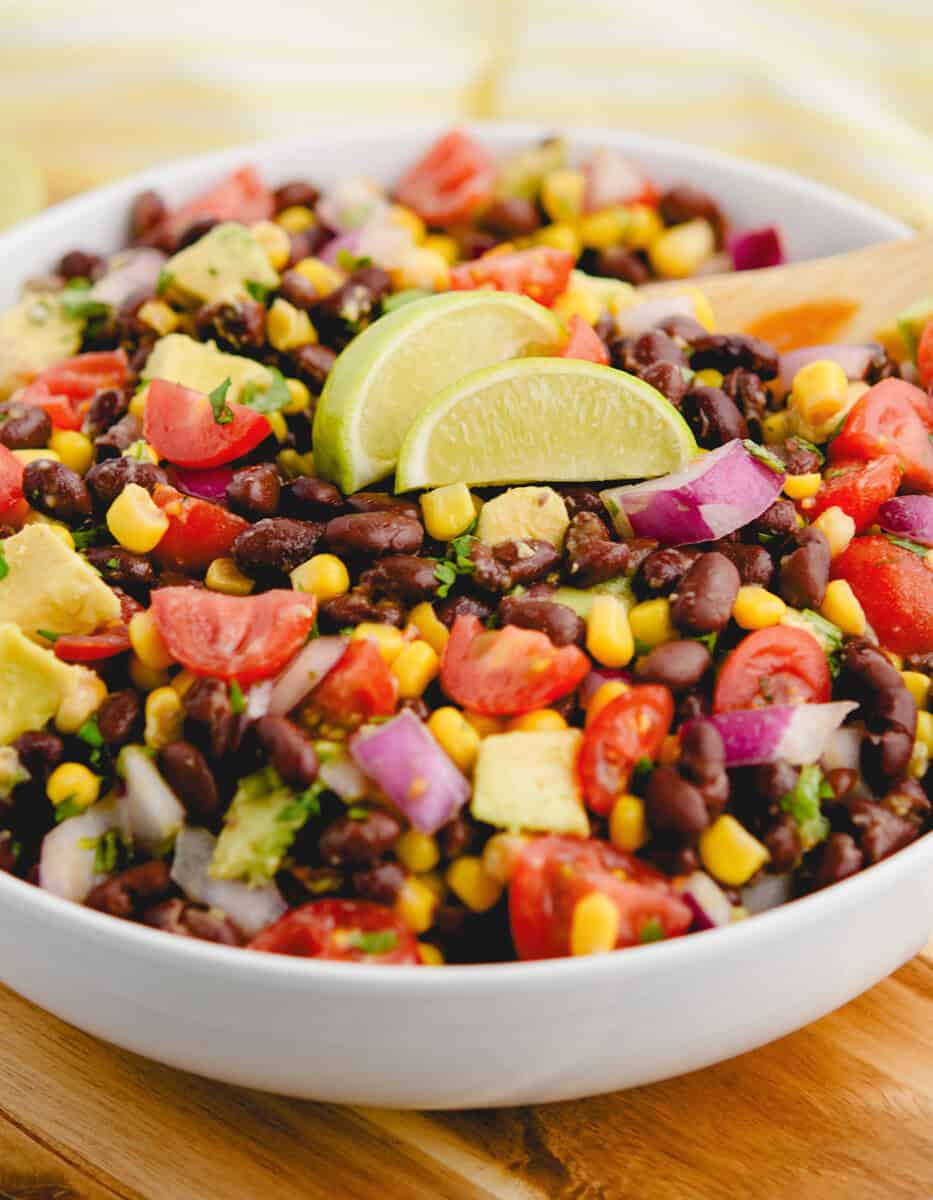 Black Bean Salad in a Bowl With Lime Wedges and Wooden Spoon
