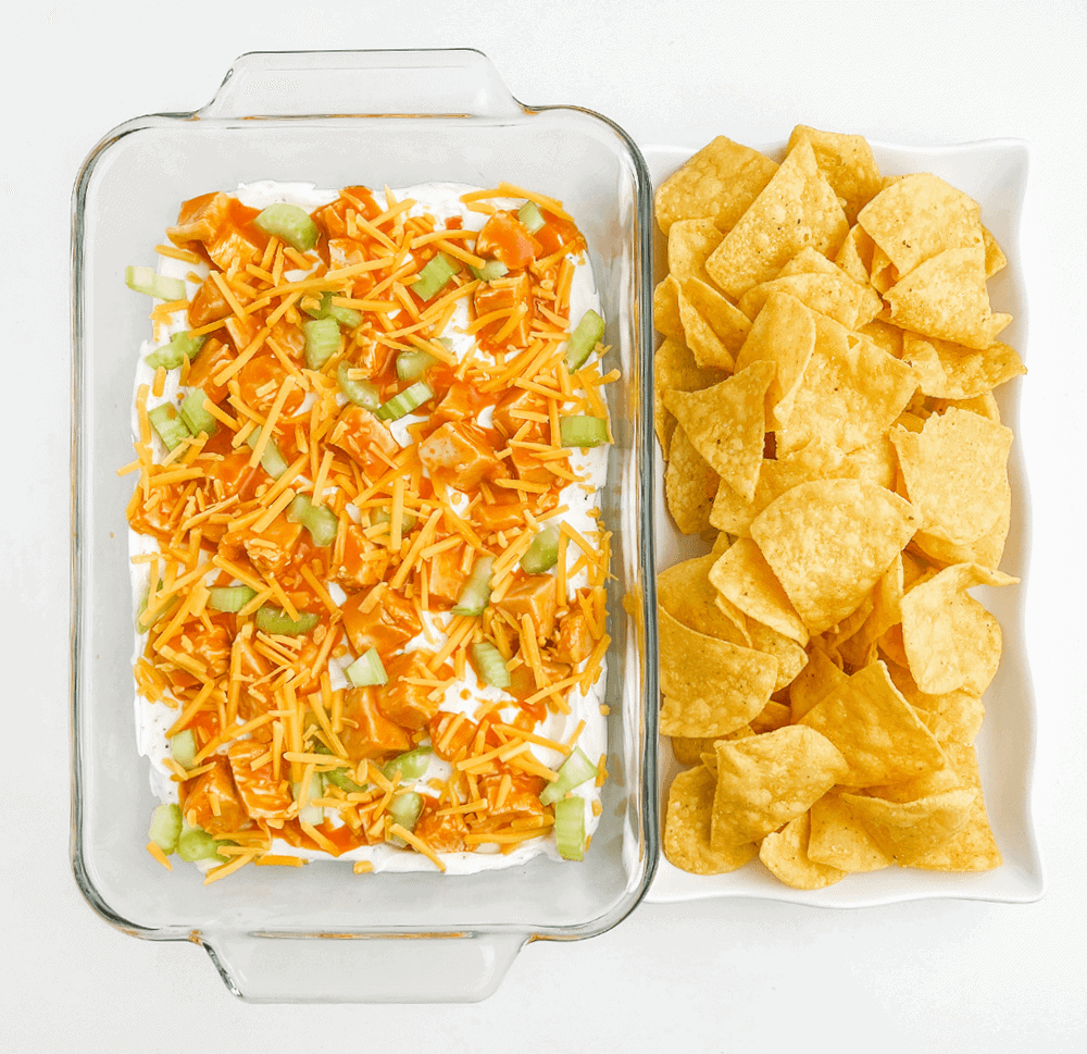 Buffalo Chicken Dip in Glass Baking Dish with White Platter of Tortilla Chips