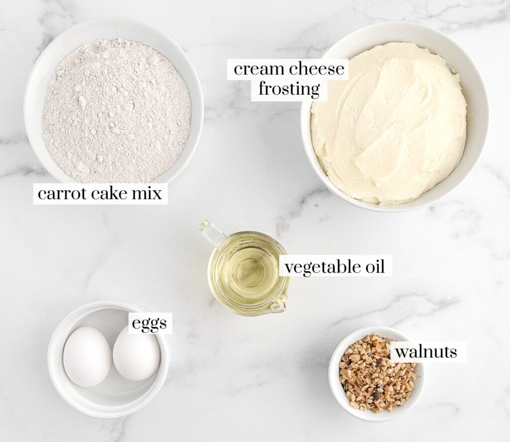 Ingredients for Carrot Cake Cookies Including Cake Mix, Eggs, Oil, Cream Cheese Frosting, and Walnuts in Bowls and Labeled