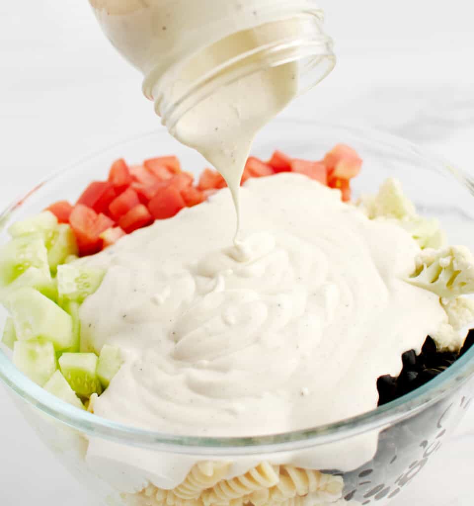 Adding Ranch to Pasta Salad in Glass Bowl
