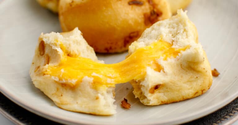 Cheesy Onion Pull Apart Bread Cut in Half with Melty Cheese Inside on a Plate
