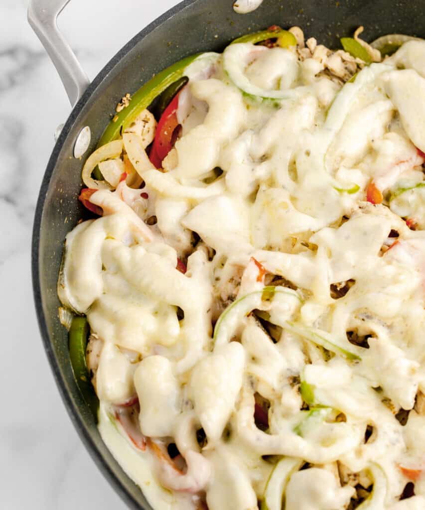 Melted Cheese On Top of Chicken and Veggies in Skillet