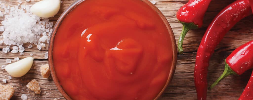 Hot Sauce in a Bowl with Fresh Peppers Surrounding