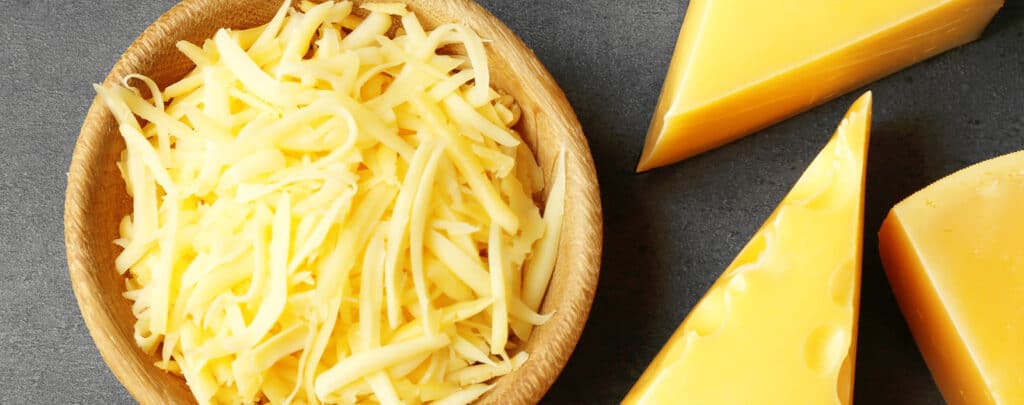 Bowl of Shredded Cheese and Blocks of Cheese
