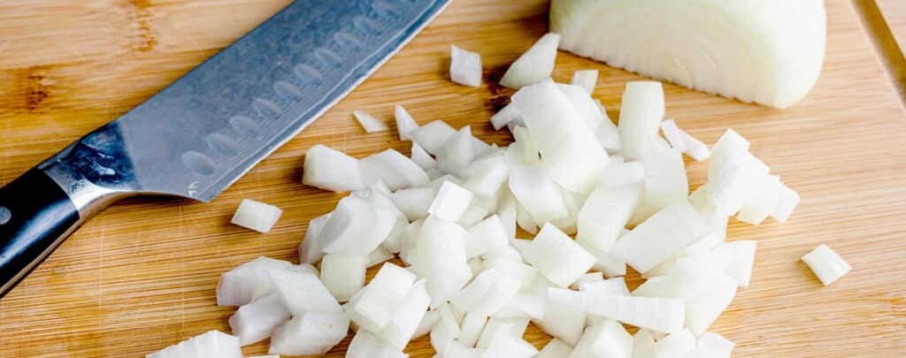 Chopped White Onion on a Cutting Board with a Knife