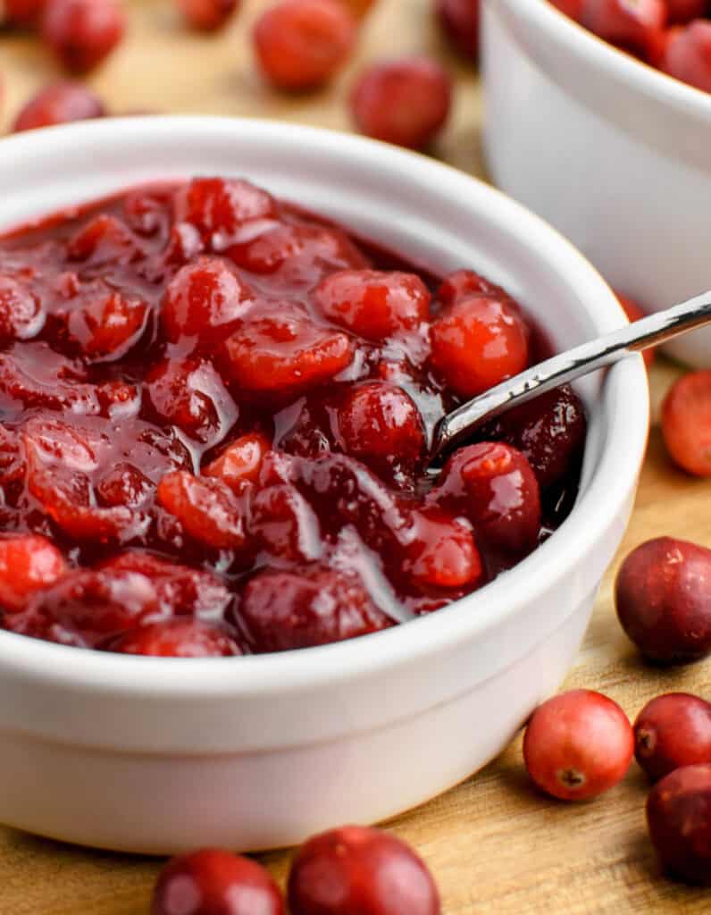Cranberry Sauce in Bowl with Spoon and Fresh Cranberries Surrounding