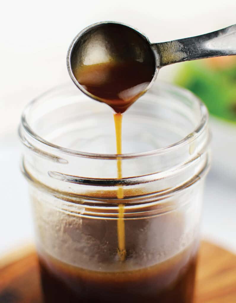 Dijon Balsamic Vinaigrette in a mason jar with a measuring spoon