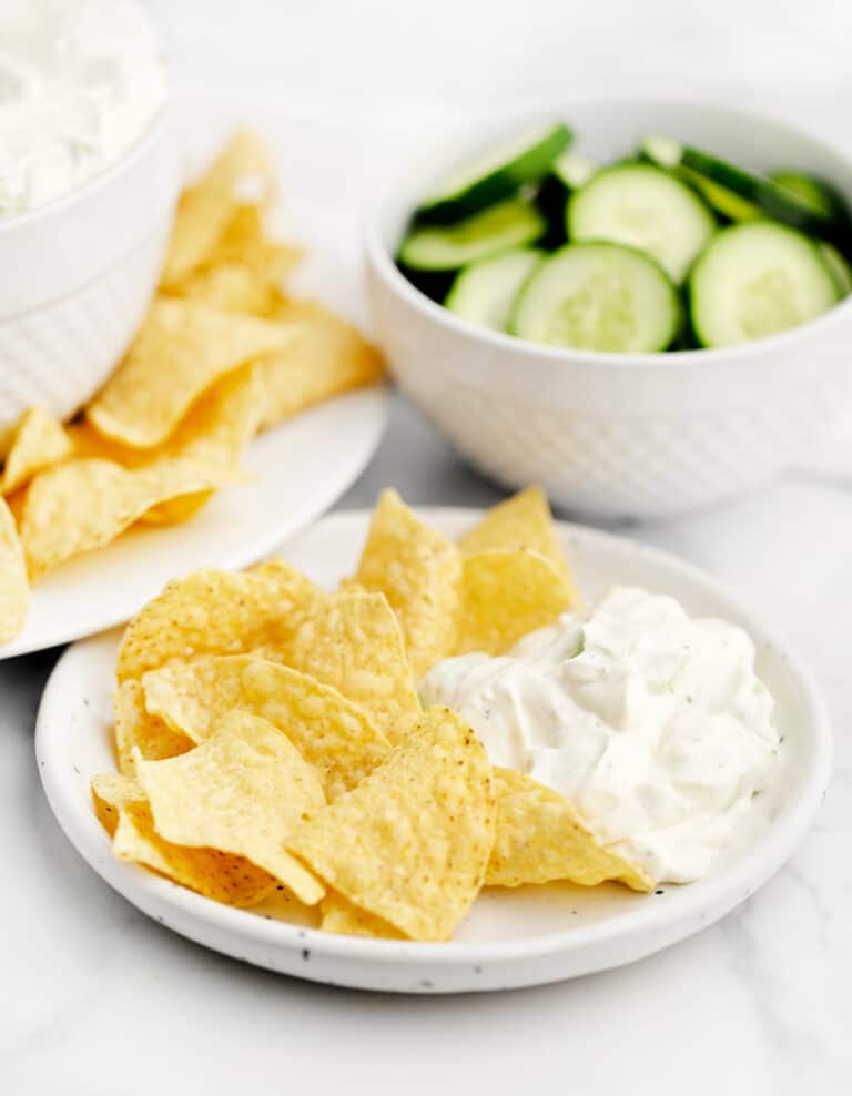 Cucumber Dip on Plate with Tortilla Chips and Bowl of Cucumbers in the Background