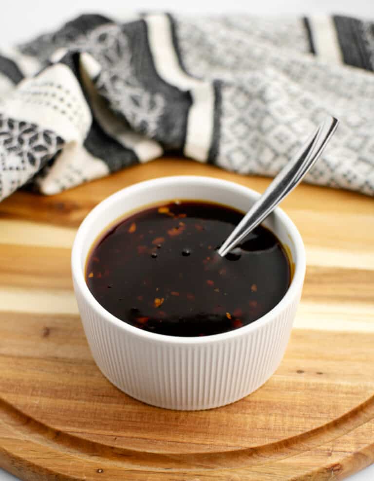 Homemade Teriyaki Sauce in Bowl on Wooden Surface with Kitchen Towel in Background