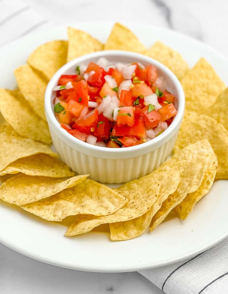 Fresh Pico de Gallo in Bowl with Circle of Tortilla Chips Around It on White Napkin with Black Stripes