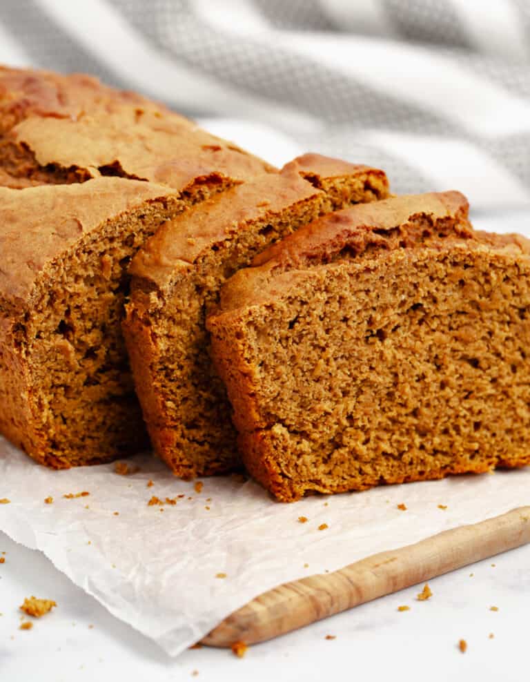 Pumpkin Bread Sliced on Wooden Board and Parchment and Stripe Towel in Background