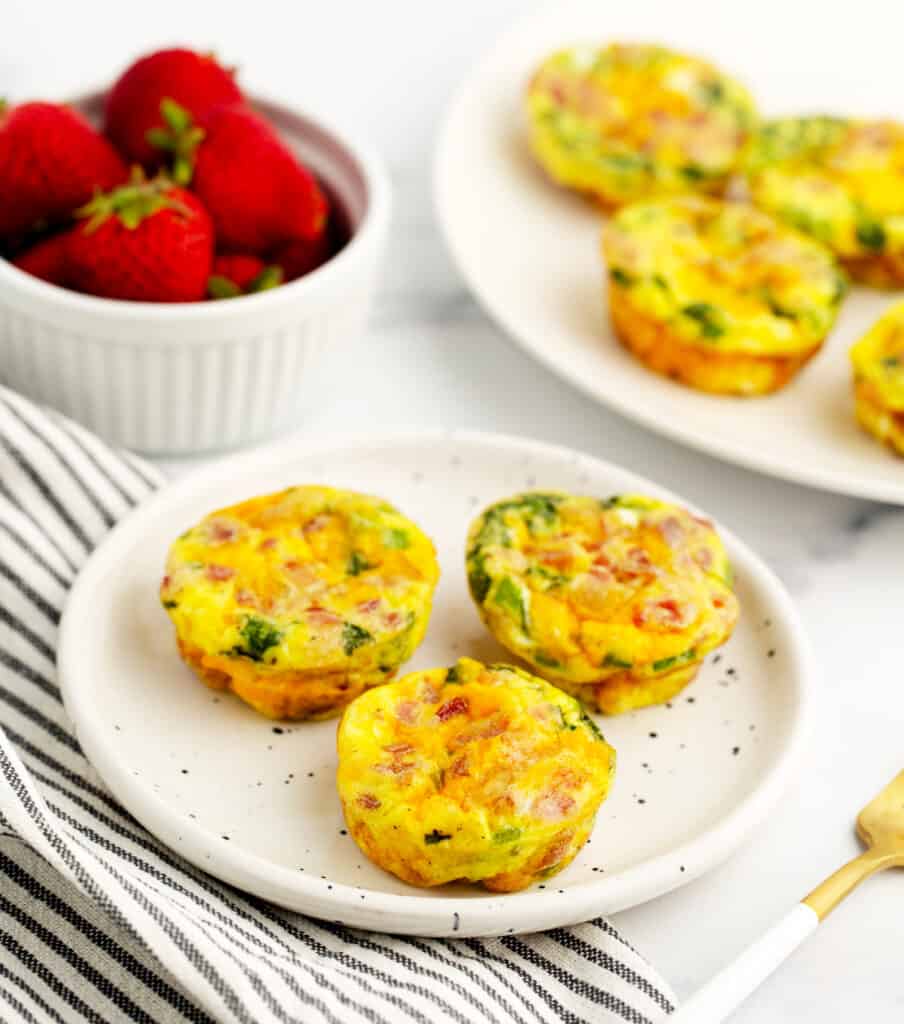 Egg Bites on Plate with Egg Bites and Strawberries in the Background