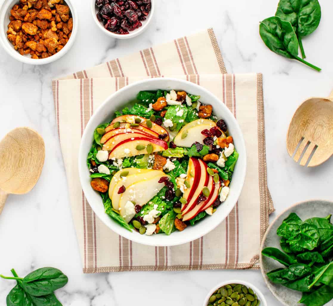Top Down View of Fall Salad on Striped Napkin with Spinach and Wooden Spoons