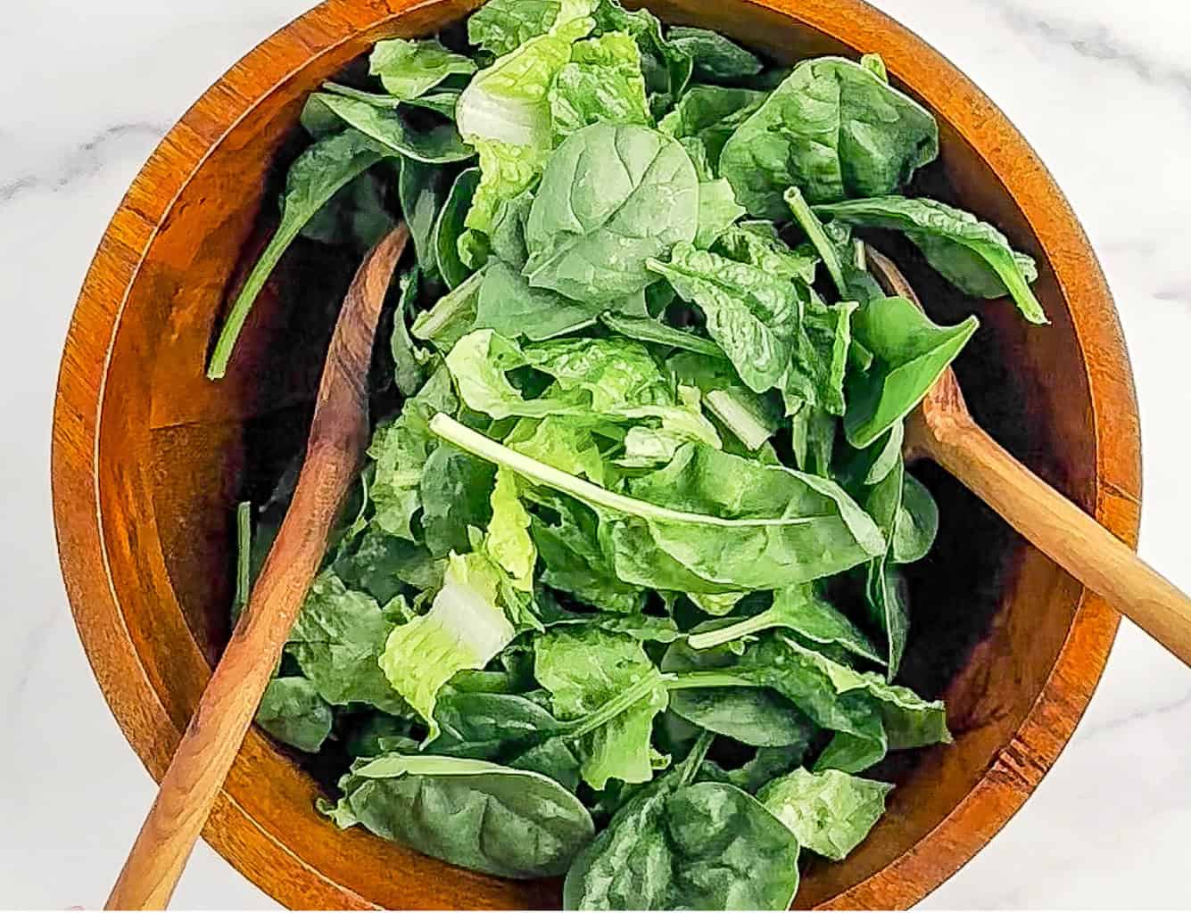 Mixing Romaine and Spinach in Wooden Bowl