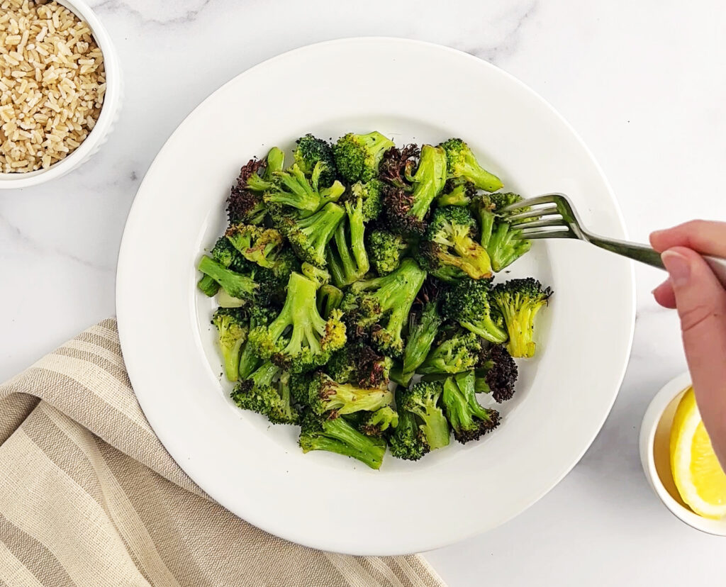 Plated Air Fried Broccoli with Fork and Sides of Rice and Lemon