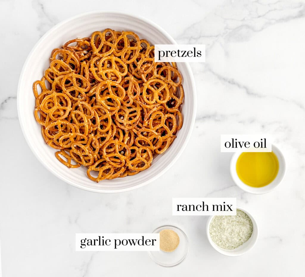 Pretzels, Oil, Ranch Mix, and Garlic Powder in Bowls on White Marble Counter