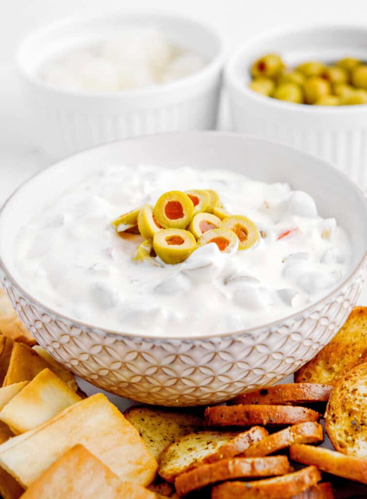 Green Olive Dip in Bowl with Crackers, Pita Chips, and Bagel Chips