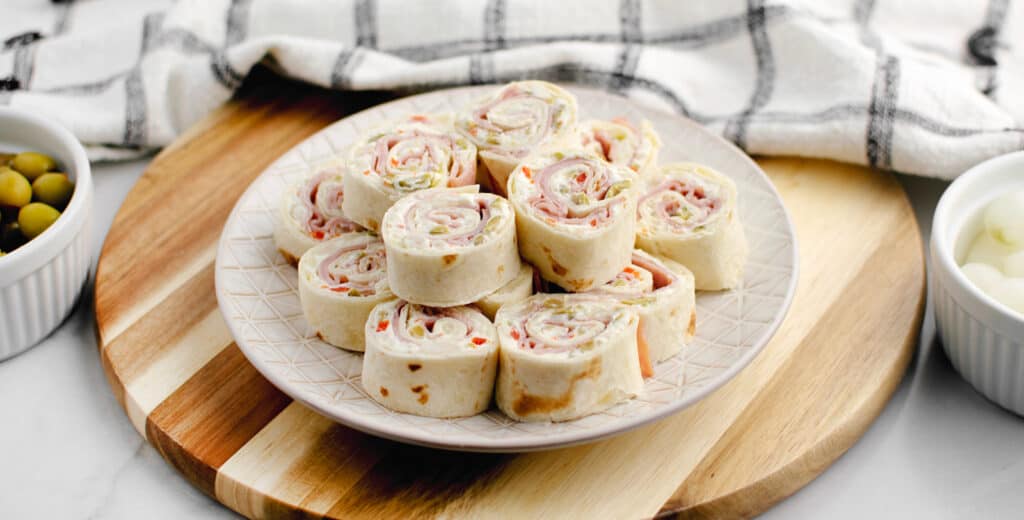 Green Olive, Ham, Cream Cheese Rollups on Serving Plate with Kitchen Towel in Background