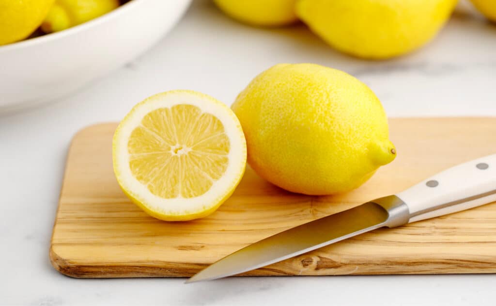 Lemon Half with Knife and Whole Lemon on Cutting Board