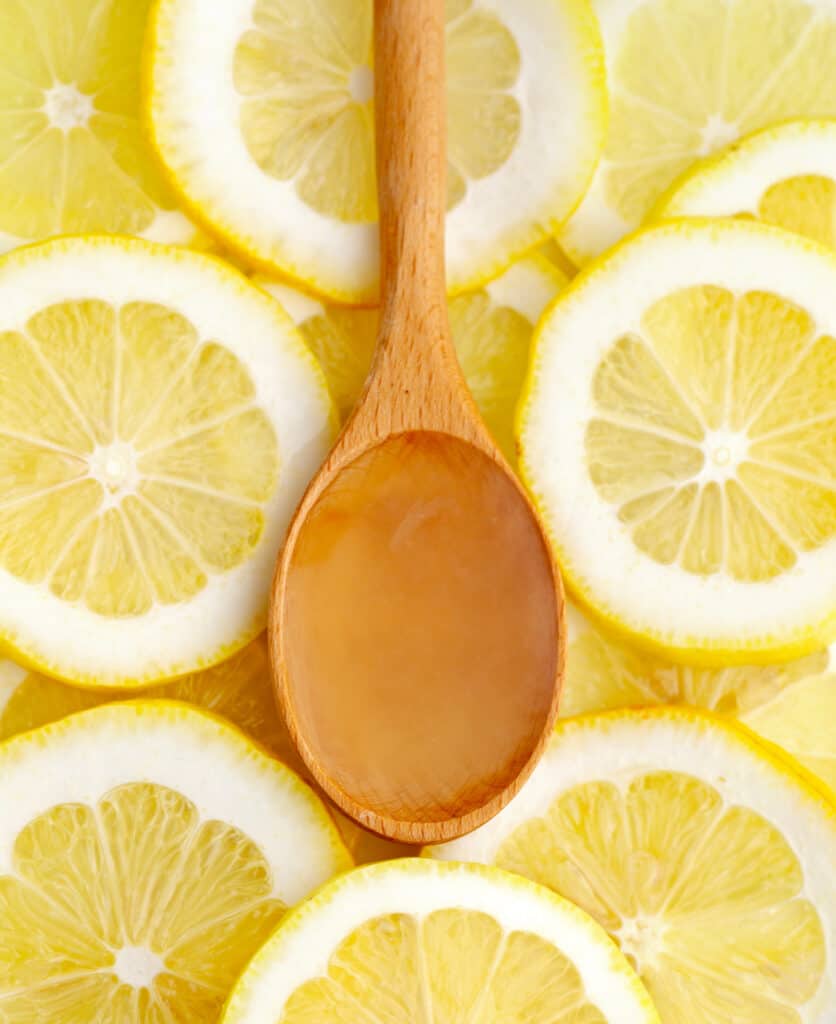 Wooden Tablespoon of Lemon Juice on Top of Lemon Slices