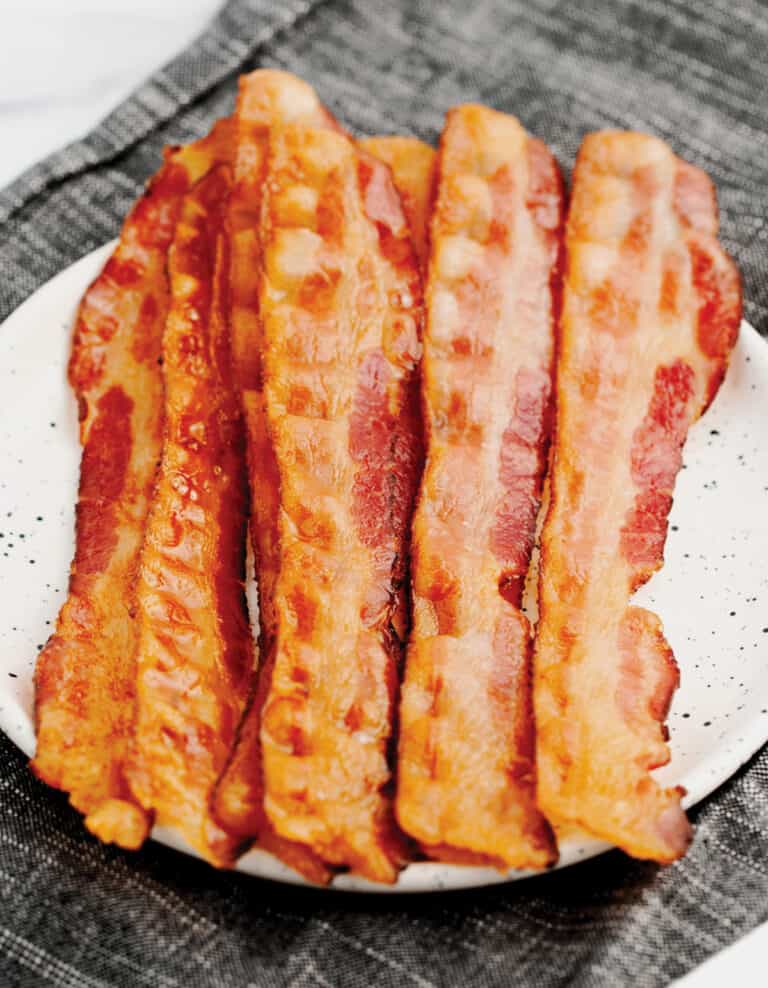 Cooked Bacon on Speckled Plate on Dark Kitchen Towel