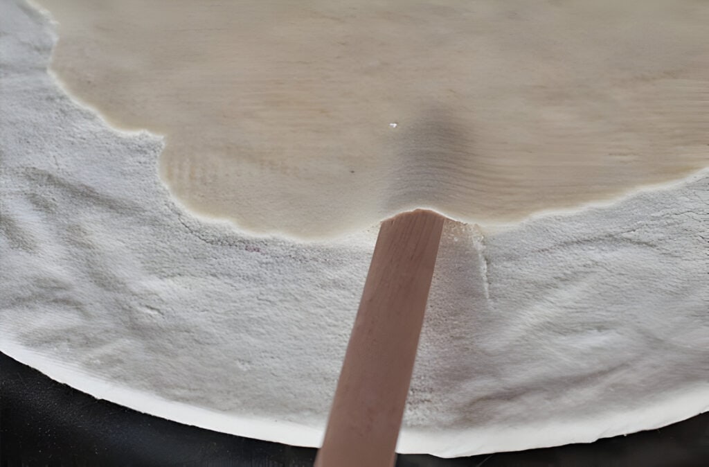 Sliding Lefse Stick Under Rolled Out Lefse Dough to Pick Up