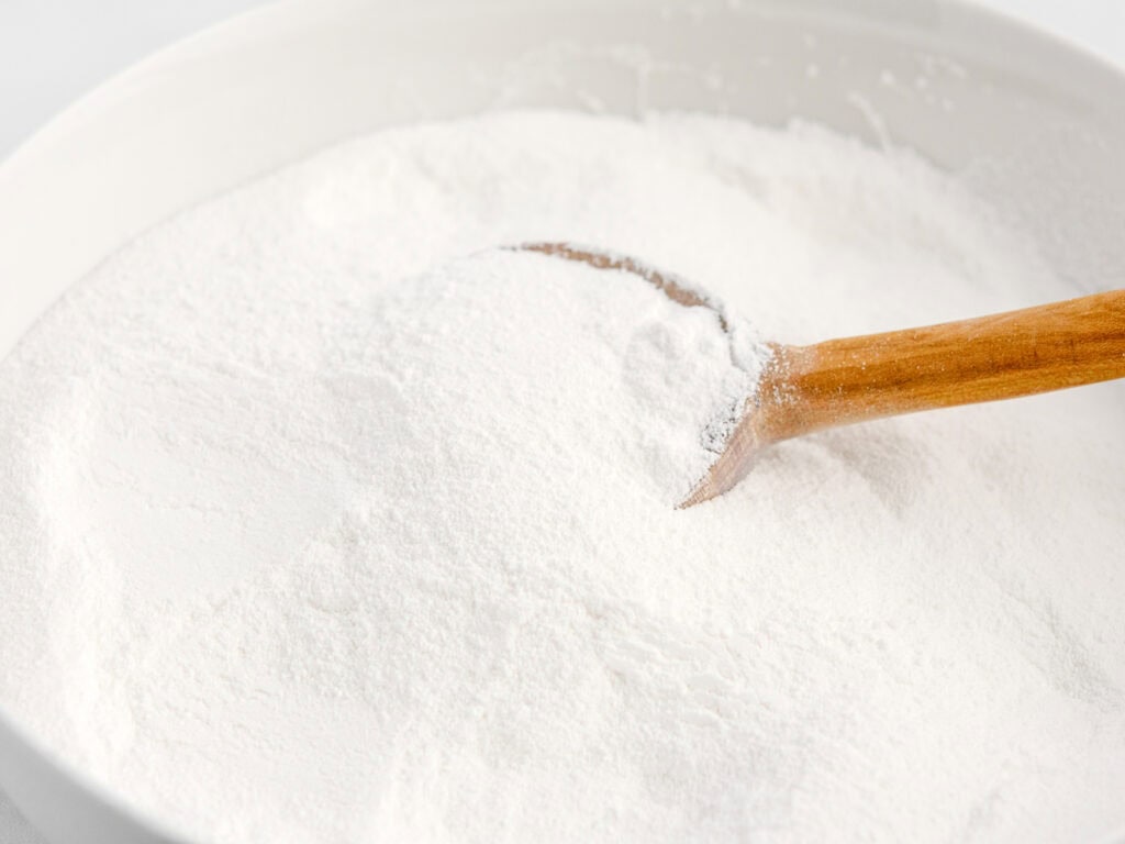 Powdered Sugar in White Bowl with Wooden Spoon