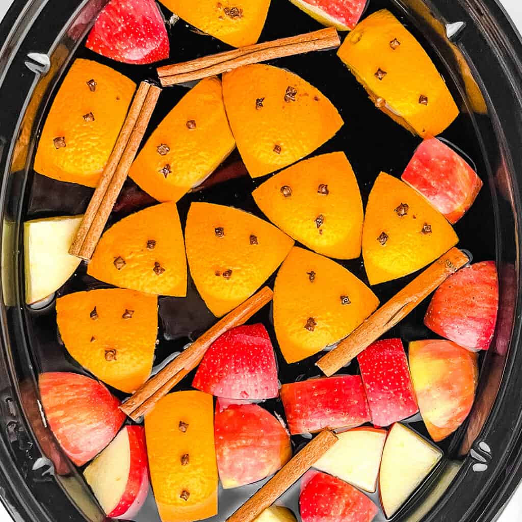 Apple Cider in Slow Cooker with Oranges, Apples, Cinnamon Sticks, and Cloves