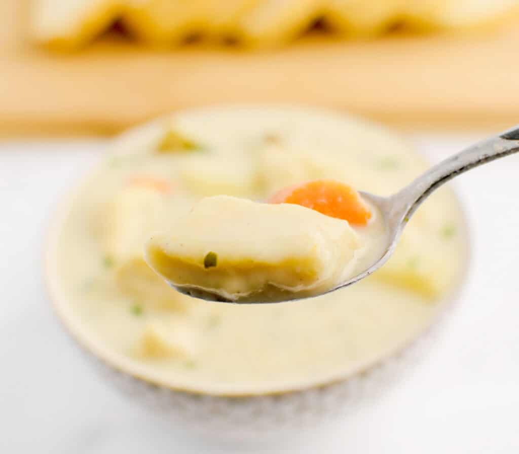 Knoephla Noodle and Carrot on Spoon with Bowl of Soup in Background