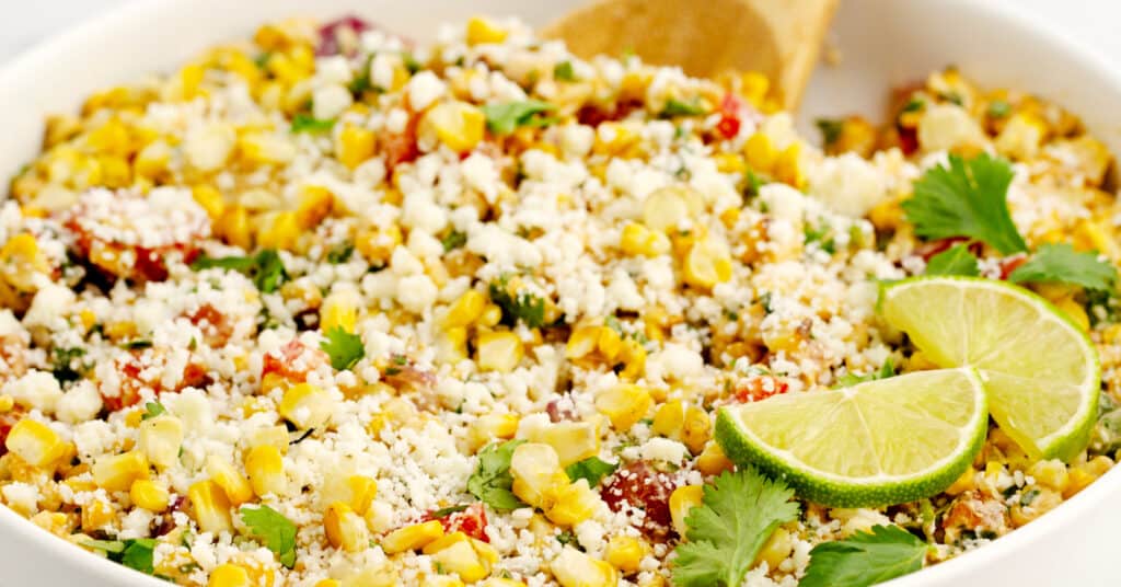 Mexican Street Corn Salad in White Bowl with Limes