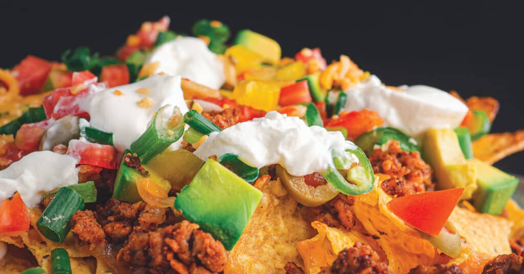 Nachos Loaded with Toppings Including Meat, Onions, Salsa, Sour Cream
