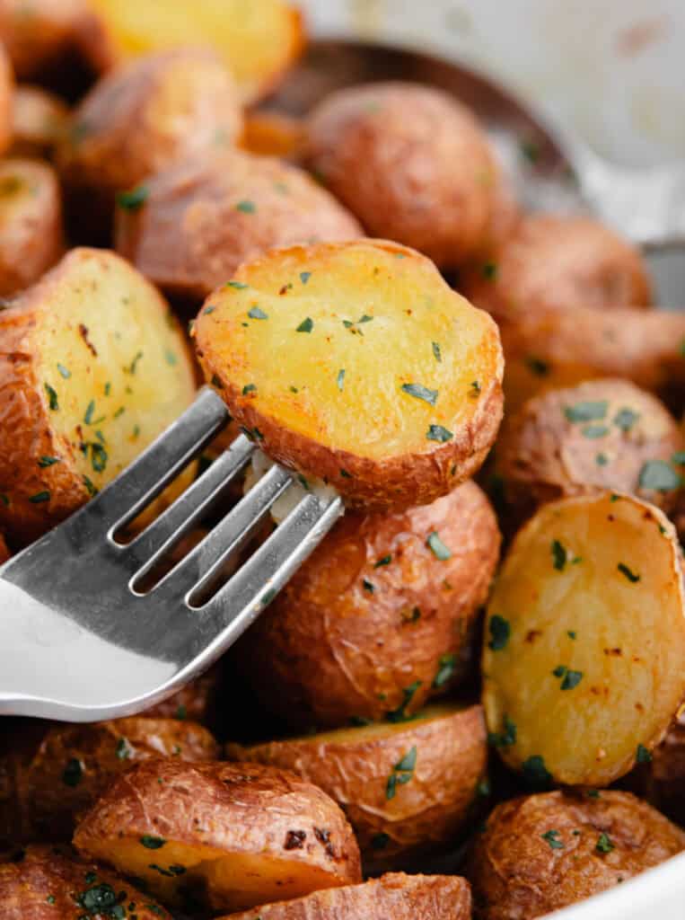 Roasted Potato on Fork with More Potatoes in Background