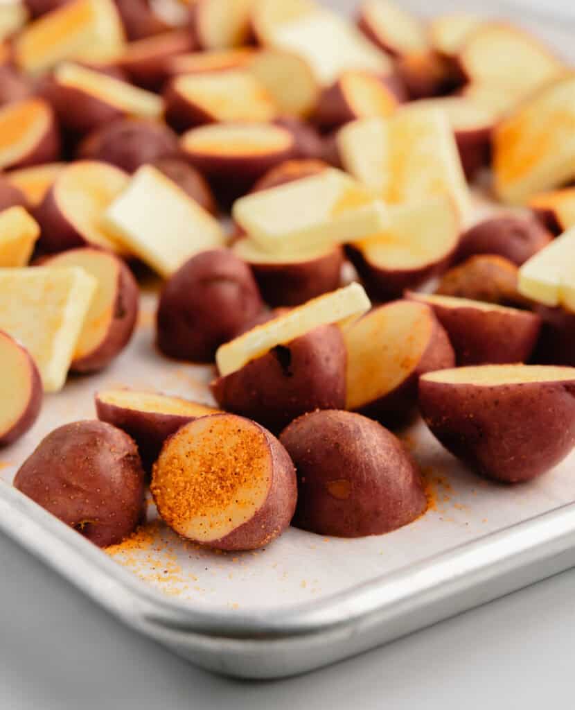 Raw Potatoes with Seasoned Salt and Butter on Baking Sheet