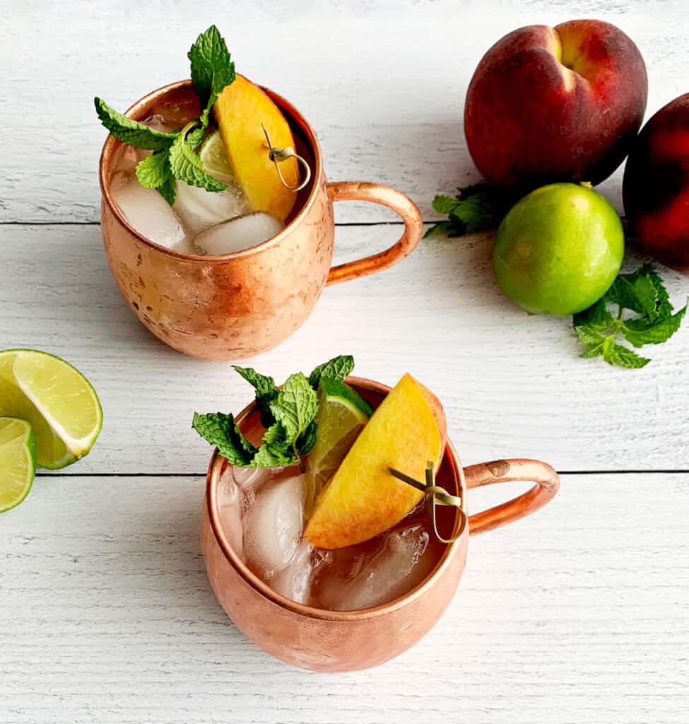 Peach Flavored Moscow Mules in Copper Mugs on White Surface