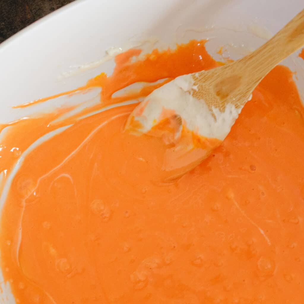Melted Marshmallows with Orange Food Coloring in Bowl with Spoon