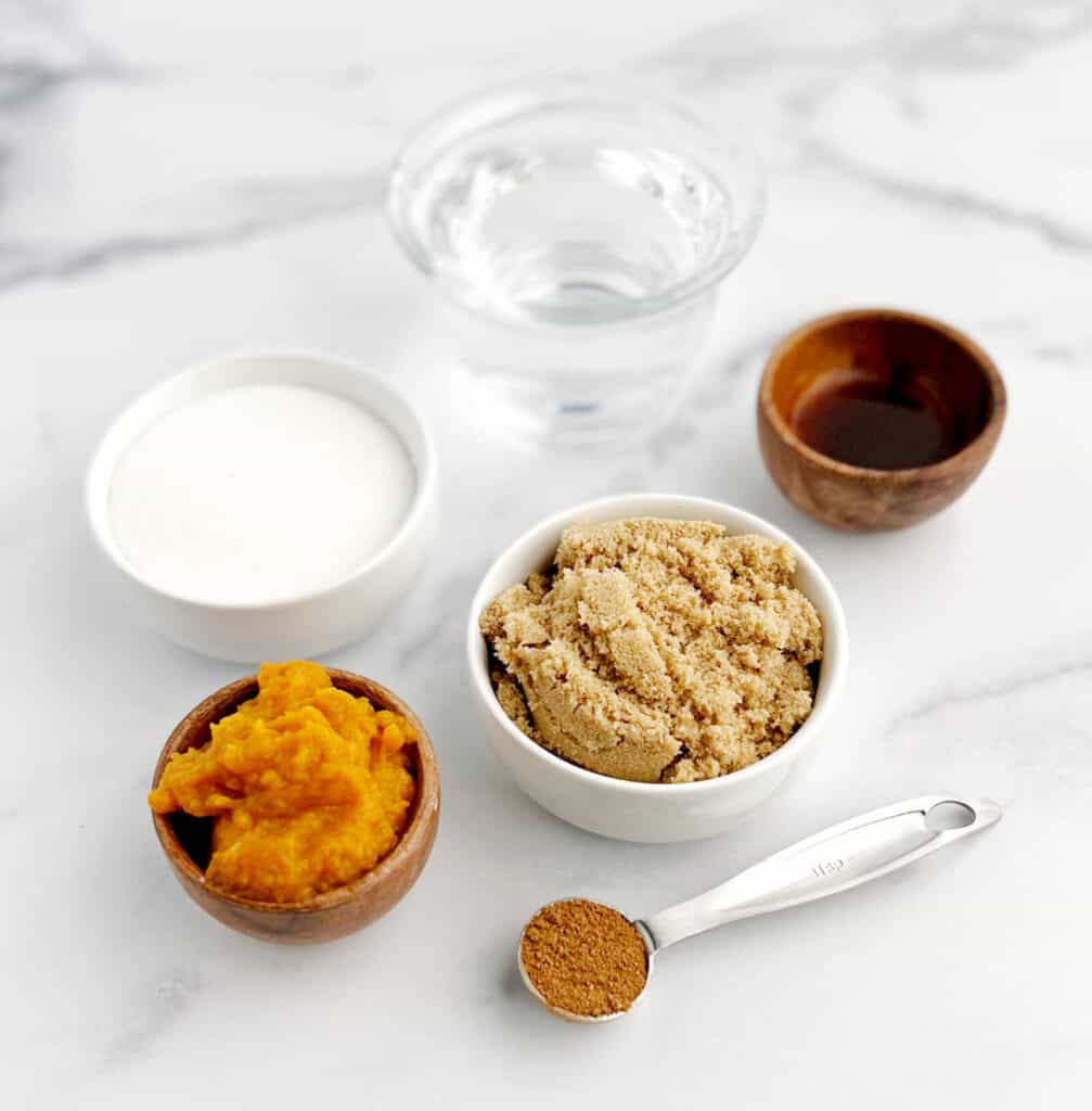 Sugar, Brown Sugar, Water, Pumpkin Puree, Vanilla, and Pumpkin Spice in Bowls on White Marble Surface
