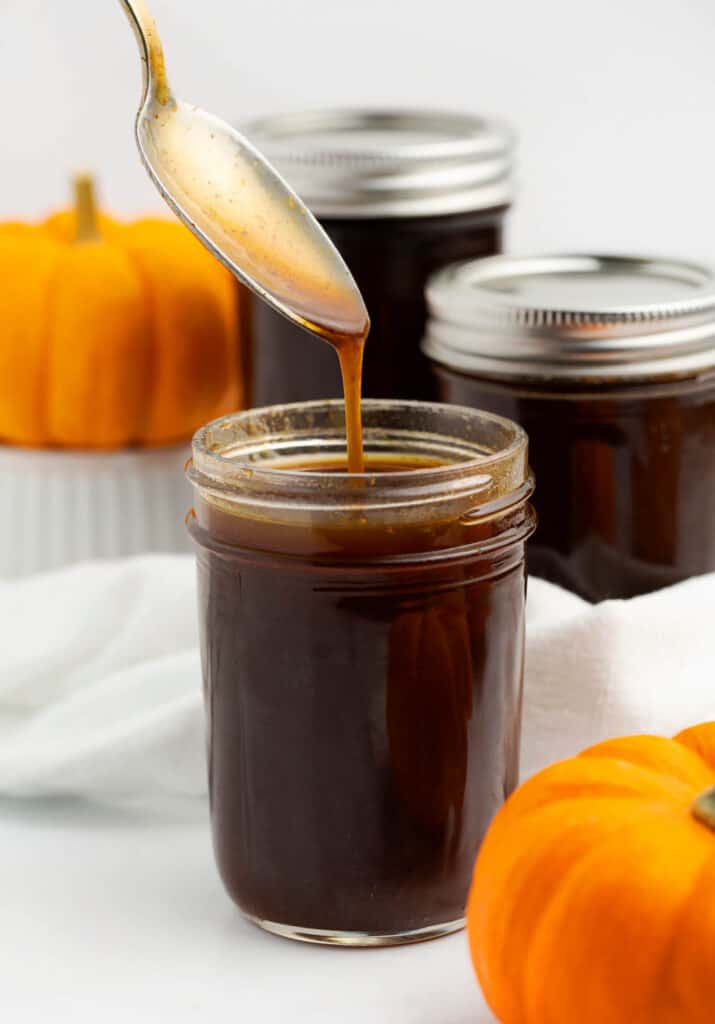 Pumpkin Spice Syrup Dripping Off Spoon into  Small Mason Jar