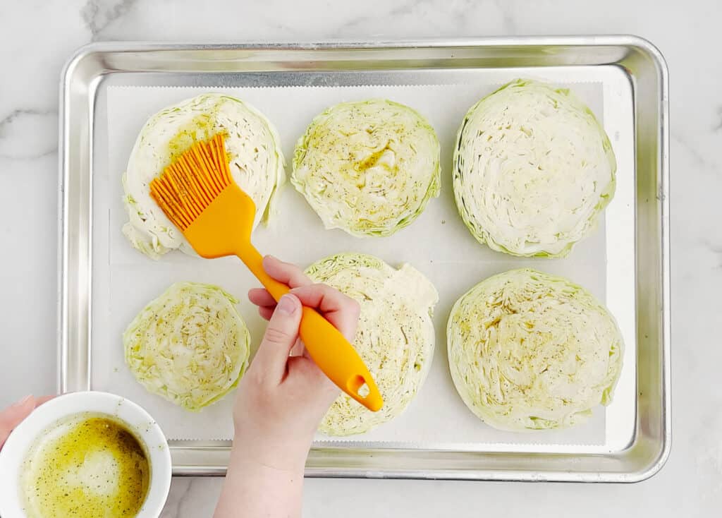 Spreading Cabbage Slices with Olive Oil Mixture on Baking Sheet