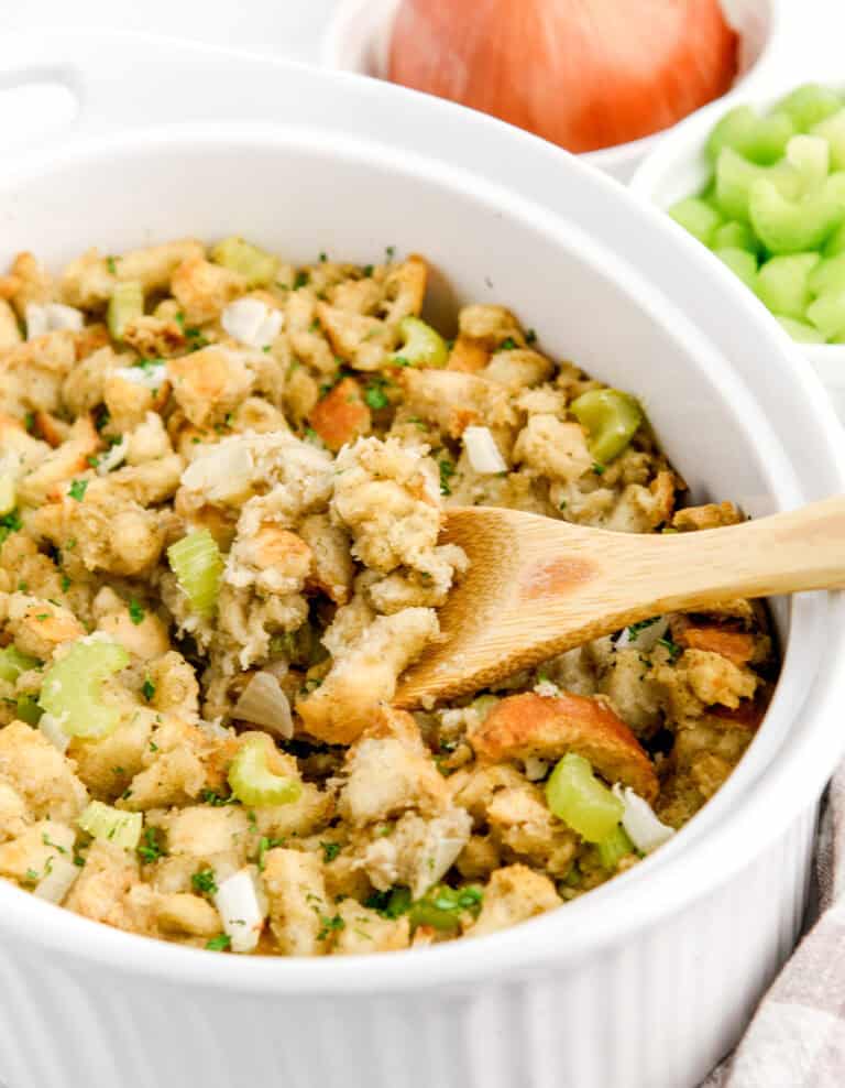 Sage and Onion Stuffing in White Baking Dish with Wooden Spoon