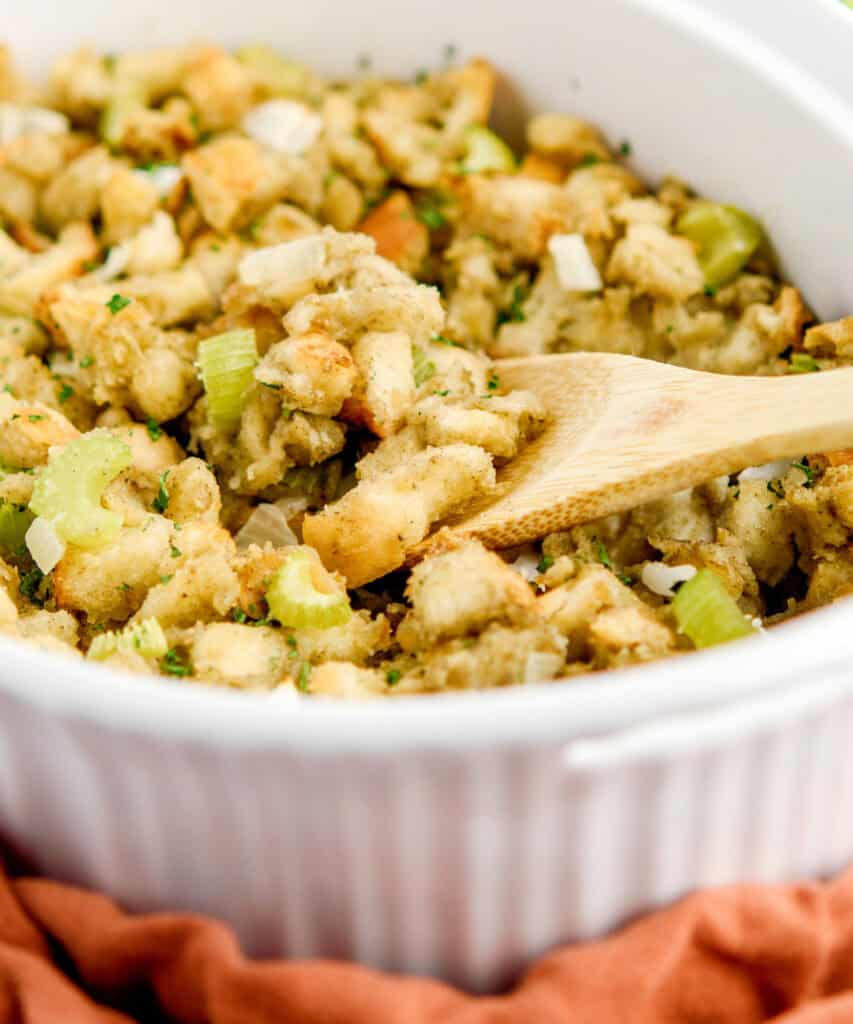 Sage and Onion Stuffing in White Baking Dish with Wooden Spoon