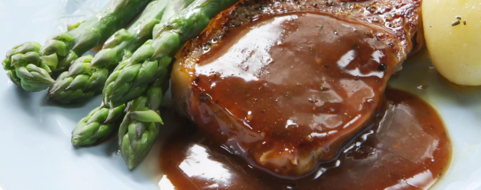 Steak Topped with Sauce and Plated with Asparagus