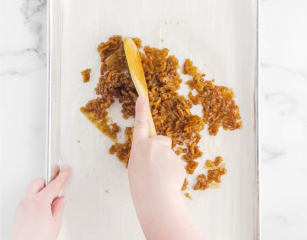Breaking Up Pretzel Mix with a Spoon on Baking Sheet