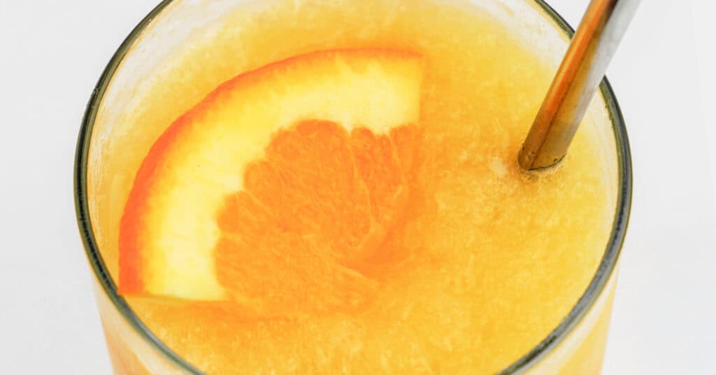 Sunrise Slush in Glass with Straw and Orange Wedge